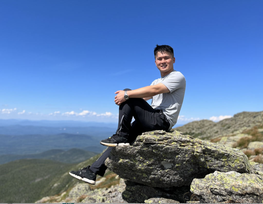 Dr. Zunwei Chen sitting posed on a rock